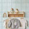 Knitted baby clothes on hanger. Nursery interior